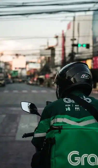 Grab delivery and ride-sharing driver on a motorcycle on an Asian city street