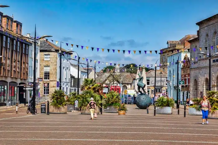 Busy Lemon Quay square in Truro with colourful bunting, palm trees, and historic buildings