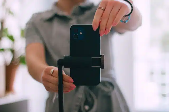 woman setting up a smartphone on a tripod for a live streaming session