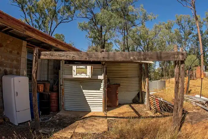 living rough in australia in a rustic outback shed with corrugated metal walls and an old fridge