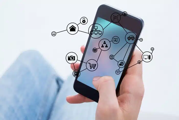 Person using a phone surrounded by floating digital icons representing internet-connected services and apps