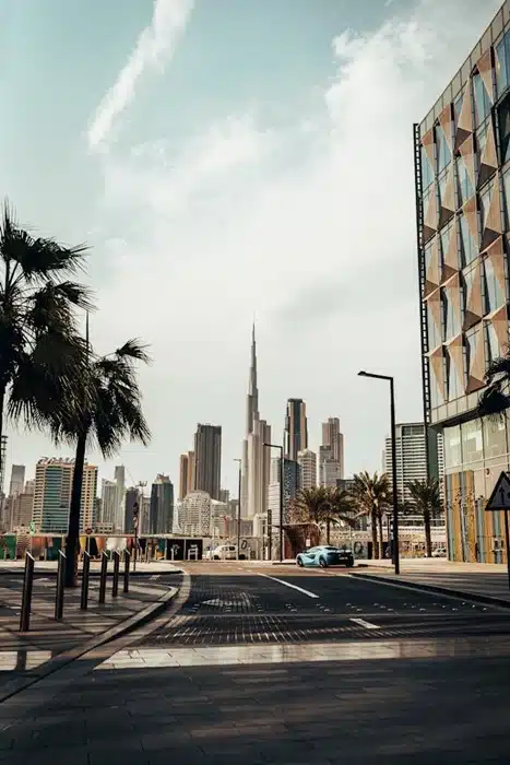 Moving to Dubai — a quiet city street lined with palm trees and a sports car with the Burj Khalifa and skyline in the distance