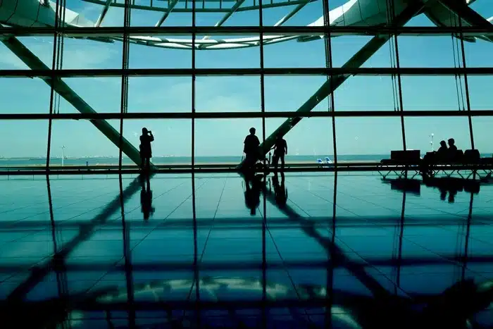 silhouettes of travelers inside a modern Asian airport terminal with large glass windows