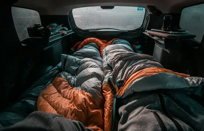 sleeping bags laid out in the back of a vehicle as a rough shelter alternative on the road