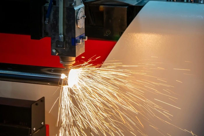 close-up of an industrial plasma cutter slicing through a metal sheet with sparks flying in a fabrication shop