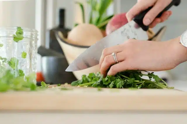 Preparing fresh herbs on a wooden chopping board in a New Zealand apartment kitchen