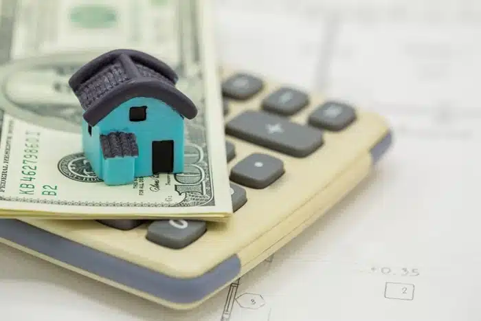 miniature house on cash and calculator representing timeshare ownership costs and returns