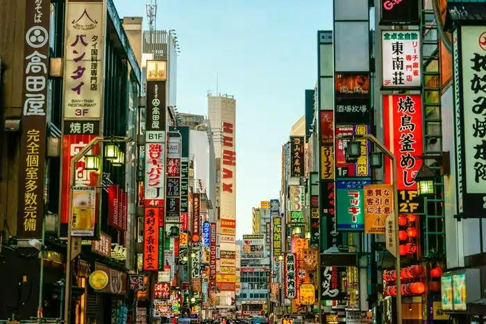 busy Japanese street lined with colorful neon signs and local shop vendors