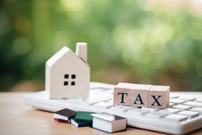 wooden tax blocks and a model house on a calculator representing tax residency rules for expats living overseas