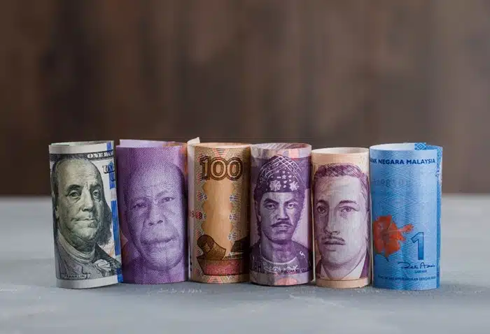 rolled banknotes in multiple world currencies lined up representing cross-border money management for expats