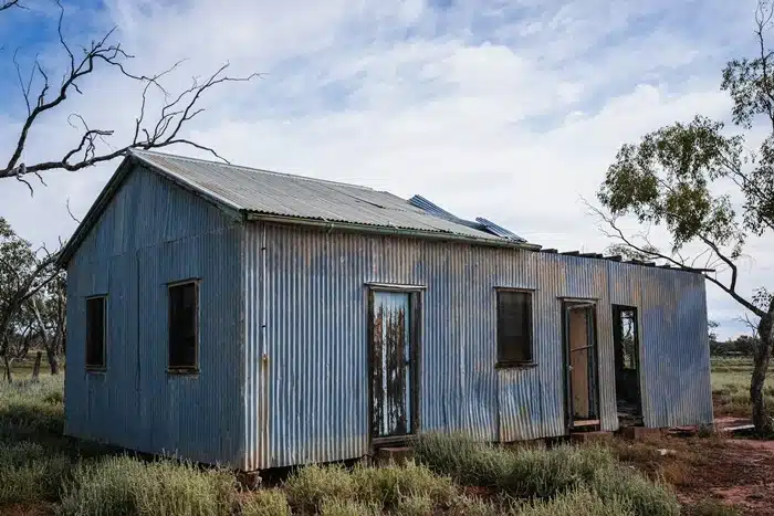 abandoned corrugated metal shearing shed in the Australian outback surrounded by dry scrubland