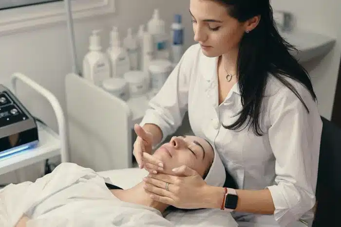 signs you need a dermatologist — esthetician assessing a client's skin during a professional consultation