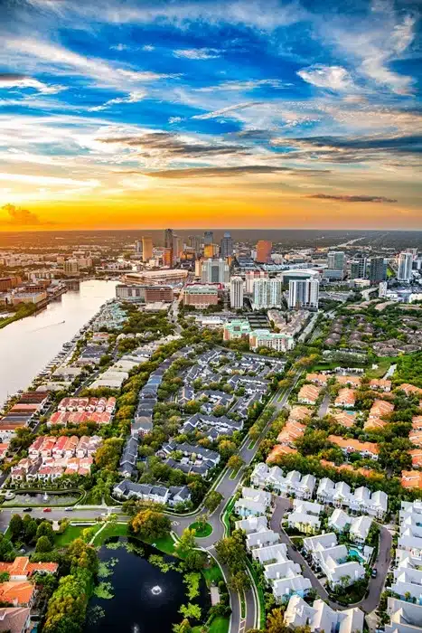Aerial view of Tampa Bay at sunset with waterfront neighborhoods, residential communities, and the city skyline in the background