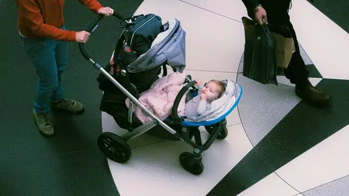 dad pushing a stroller with a baby through an airport — tips for new parents traveling