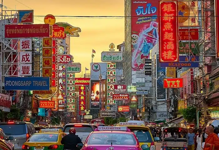 heavy traffic and colorful signs lining the streets of Chinatown in Bangkok at sunset
