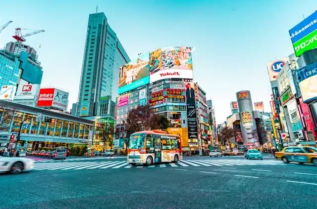 traveling around Japan through a busy Tokyo intersection with colorful billboards and city traffic