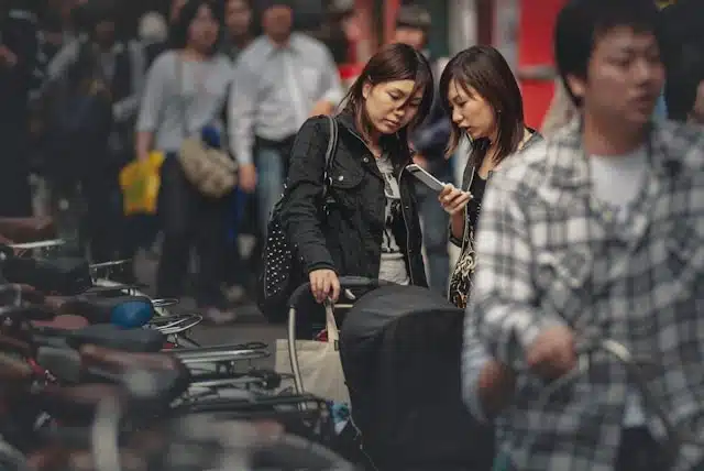 two women checking a phone while traveling Japan with portable WiFi in a crowded street market