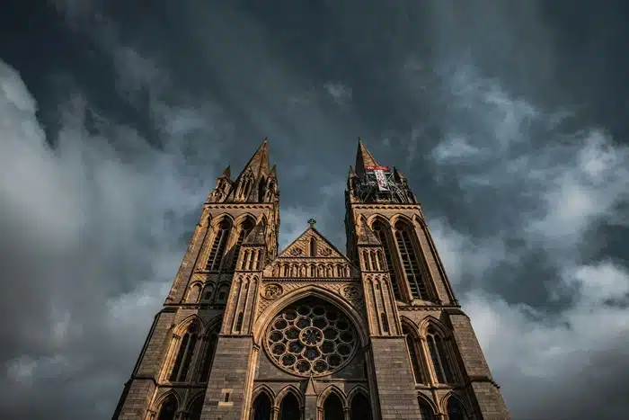 The Gothic facade of Truro Cathedral with twin spires against a dramatic stormy sky