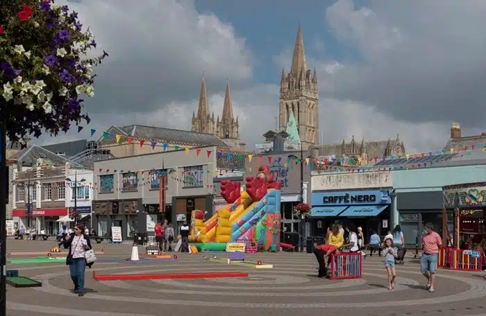 Shoppers and a bouncy castle in Truro city centre with the Cathedral towers visible above the rooftops