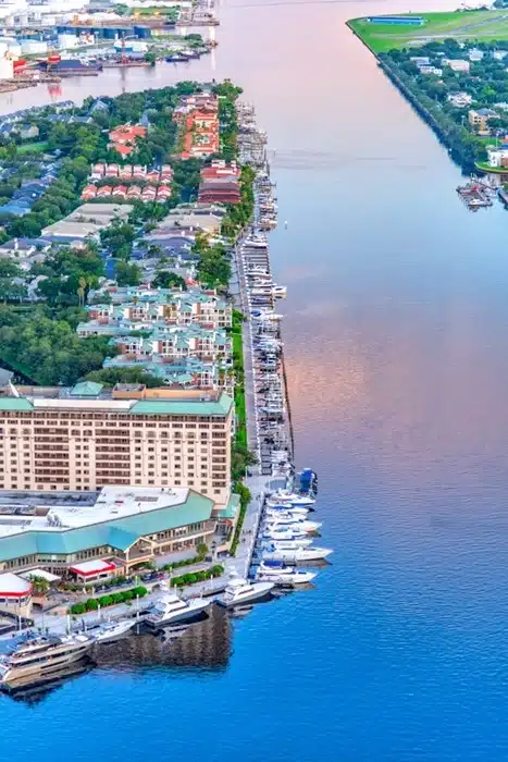 Aerial view of vacation homes and hotels along a Florida riverfront with a long marina lined with boats and yachts