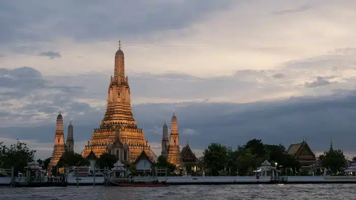 Wat Arun temple lit up at dusk viewed from across the Chao Phraya River on a private Bangkok guided tour