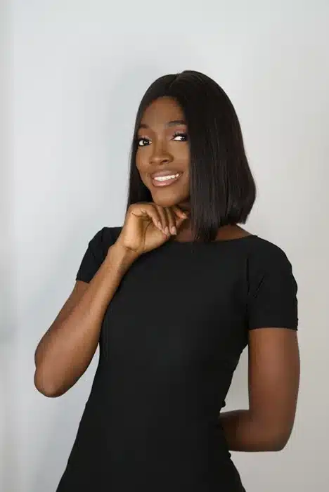 Dark-skinned woman wearing a smooth straight bob wig styled to one side in a black outfit