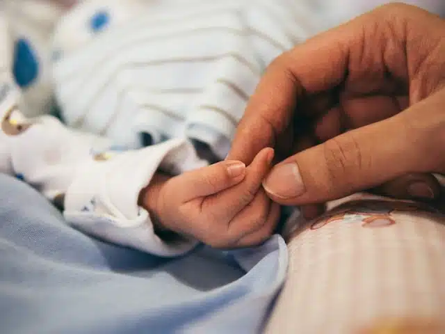 Parent gently holding their newborn's tiny hand in a close-up moment