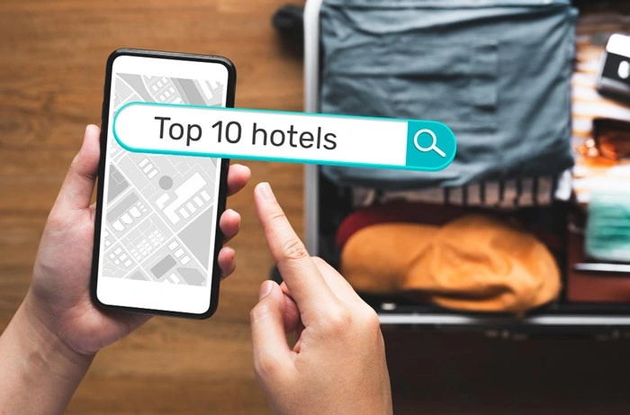Person searching for top 10 hotels on a smartphone with an open suitcase in the background