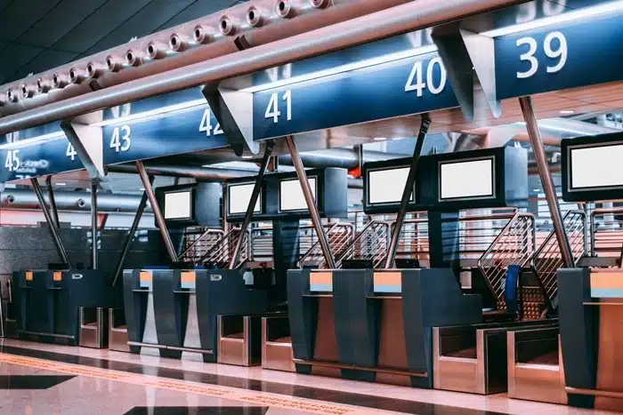 Airport check-in counters with numbered boarding gates and self-service kiosks