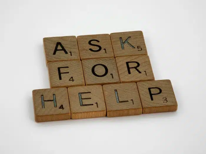 Wooden scrabble tiles spelling "ask for help," a reminder to seek support during a life transition