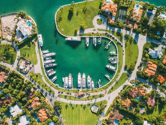 Drone shot of a Miami marina with white yachts docked along a turquoise waterway lined with palm trees