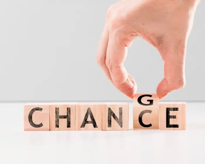 Hand flipping a wooden block from "change" to "chance," symbolizing growth during a major life change
