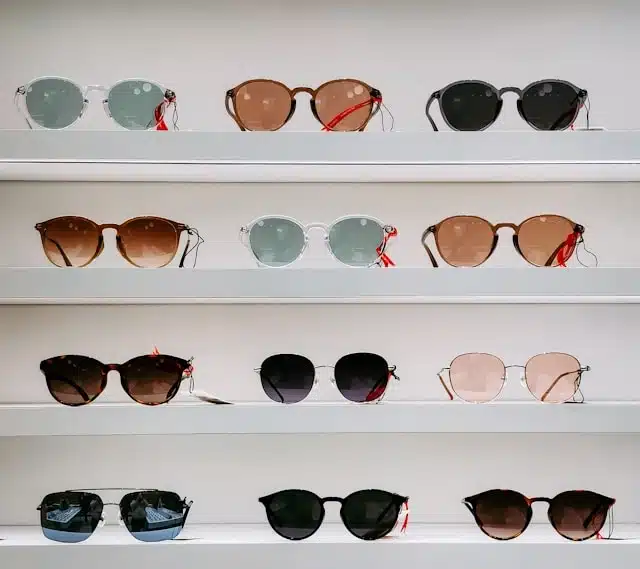 Rows of sunglasses with different lens tints and frame styles displayed on a store shelf
