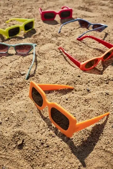 Colorful sunglasses frames scattered on sand at the beach