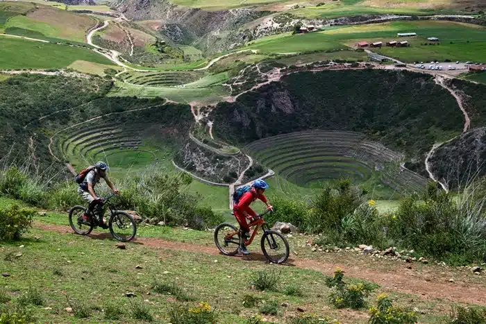 Cyclists biking near Machu Picchu on a trail overlooking Moray's circular Inca terraces