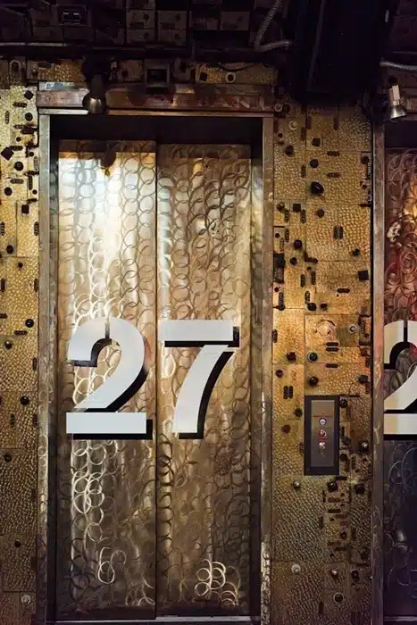 Ornate brass elevator door numbered 27 in an NYC apartment building