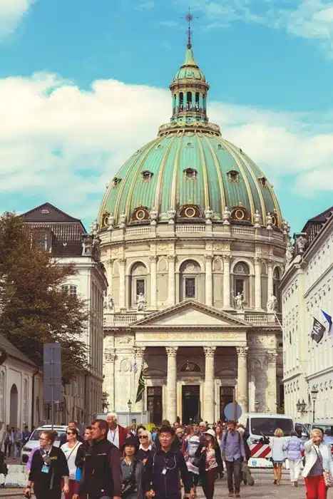 Tourists exploring the streets in front of the Frederik's Church with its iconic green copper dome in Copenhagen, Denmark