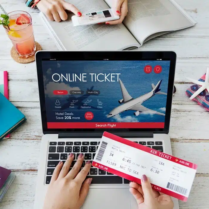 A person holding an air ticket while browsing a fake online booking site on a laptop, illustrating how fraudulent flight deals target unsuspecting travelers.