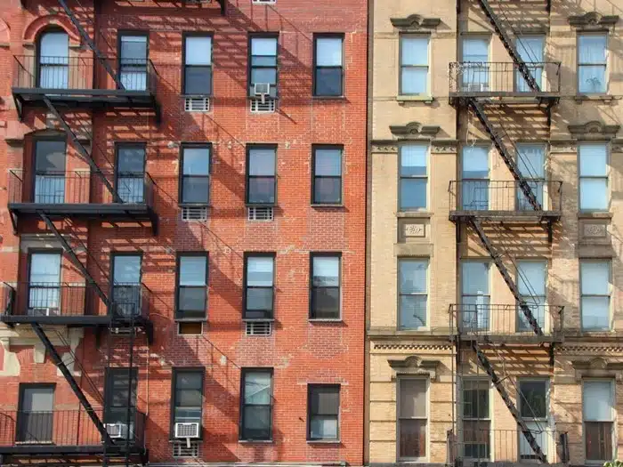 Fire escape stairs on red brick and tan apartment building facades in Manhattan