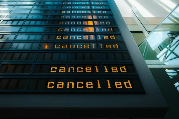 Airport departure board displaying multiple cancelled flights, highlighting the financial risks of traveling without adequate travel insurance