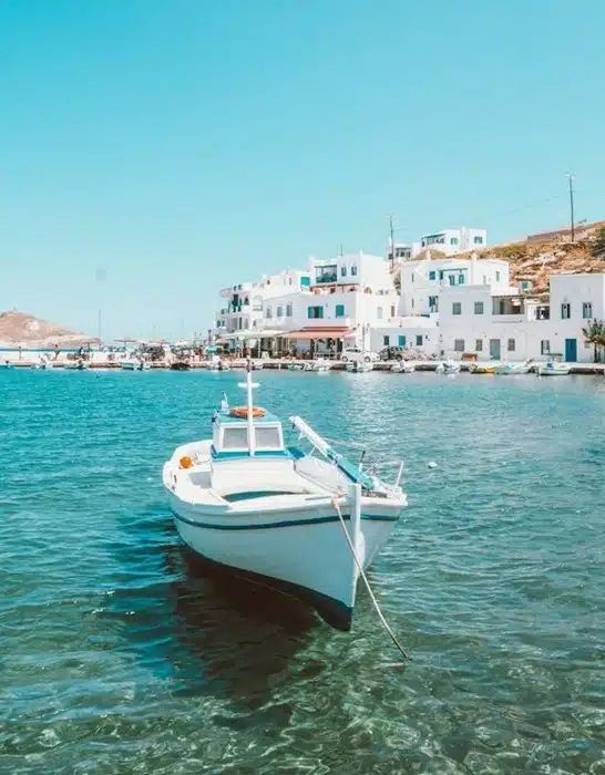 a white fishing boat moored in a calm harbor with whitewashed buildings along the coastal destinations in Europe