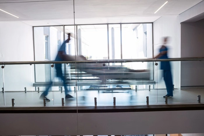 Medical staff rushing a patient on a stretcher through a hospital corridor, illustrating the high medical costs foreigners face without travel insurance abroad