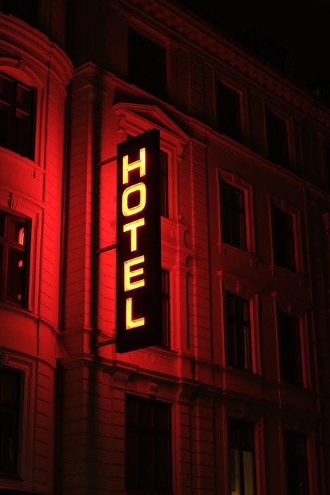 Hotel sign lit up in red at night symbolizing accommodation red flags to watch out for