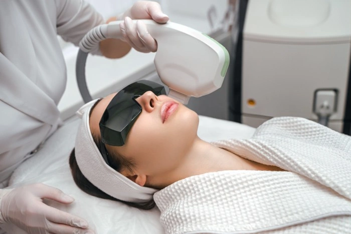 Dermatologist applying a pico laser handpiece to a woman's face during a professional skin treatment at an aesthetic clinic