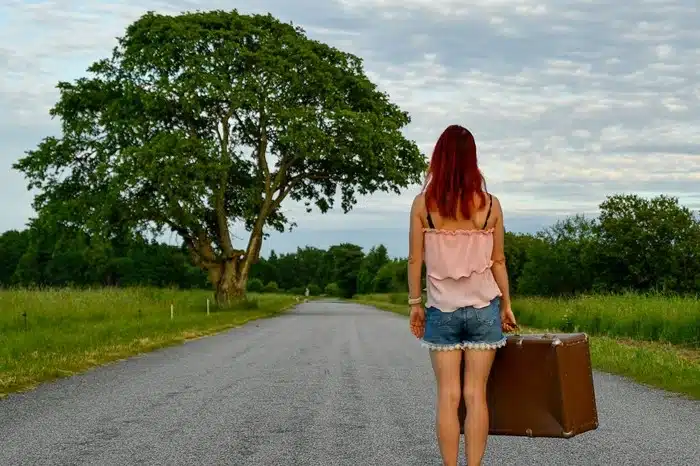 Woman walking down an open road with a suitcase, embracing a new life transition