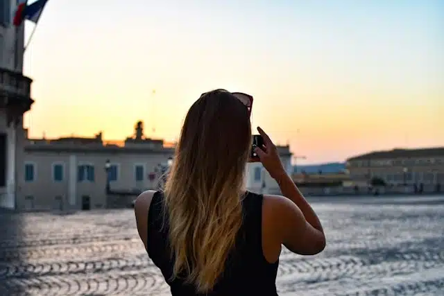 A woman taking a photo of the sunset over a European piazza on customizable private tours in Europe