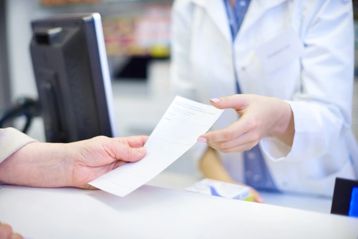 A pharmacist handing a medical bill to a patient, highlighting the steep healthcare costs tourists may face without insurance coverage abroad