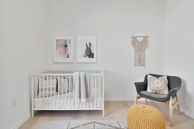 Minimalist nursery with a white crib, cozy chair, and simple decor
