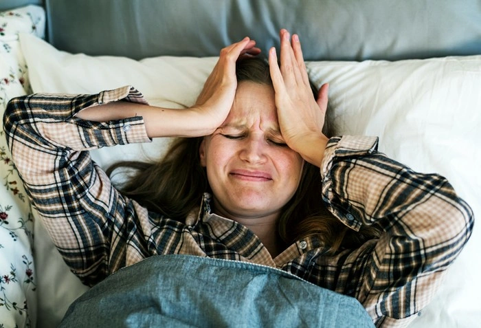 Woman lying in bed looking stressed and unable to sleep due to hotel noise disturbance