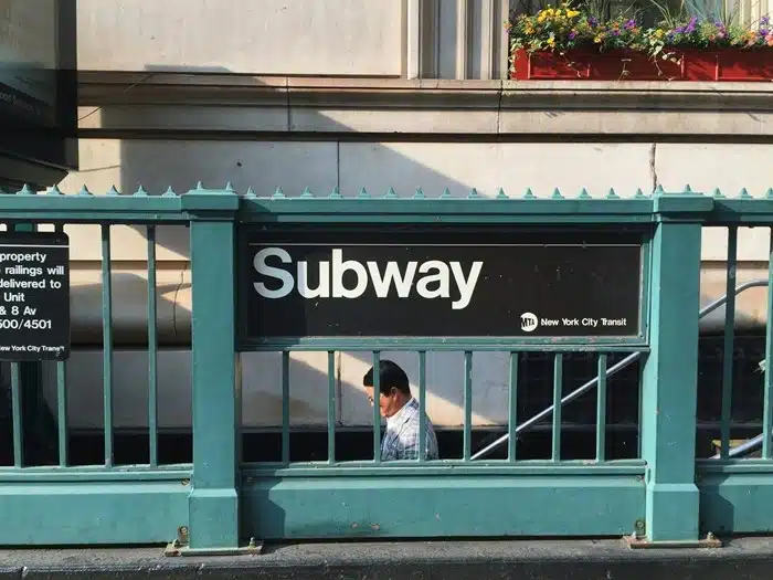 Person descending stairs into an NYC subway station entrance